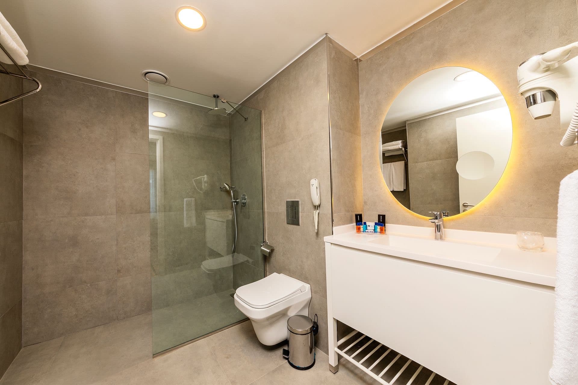 Walk-in frameless glass shower with rainfall showerhead and natural stone tile